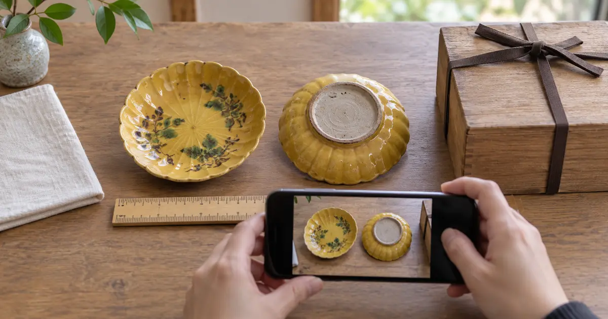 珉平焼をイメージした小皿をスマートフォンで写真査定用に撮影する様子